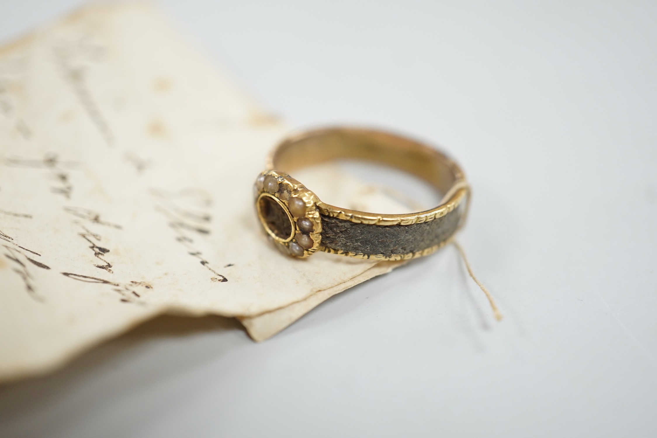 A 19th century yellow metal, split pearl and plaited hair set mourning ring, size O, gross weight 2.9 grams.